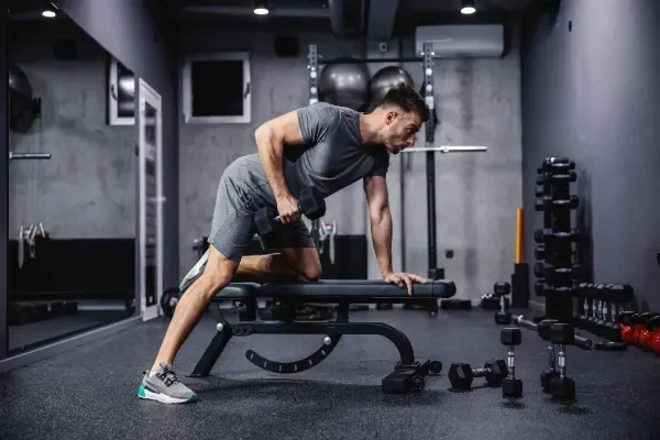 row-on-bench a man lifting weights in a gym doing rows on a bench